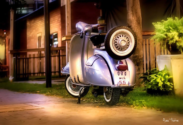 A beautifully restored 1960s Vespa motor scooter, gleaming with vibrant colors and classic design.