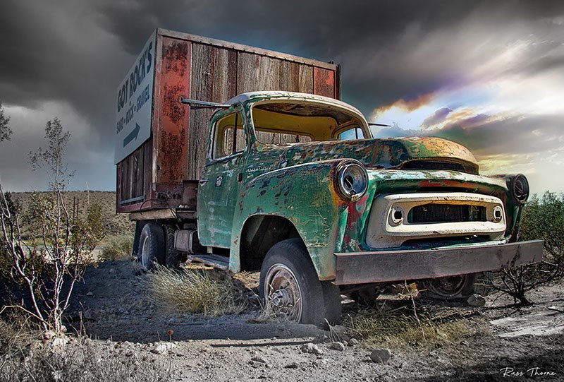 A rusty old box truck in the desert, repurposed as a highway billboard, marking the last job of this once-mighty vehicle.