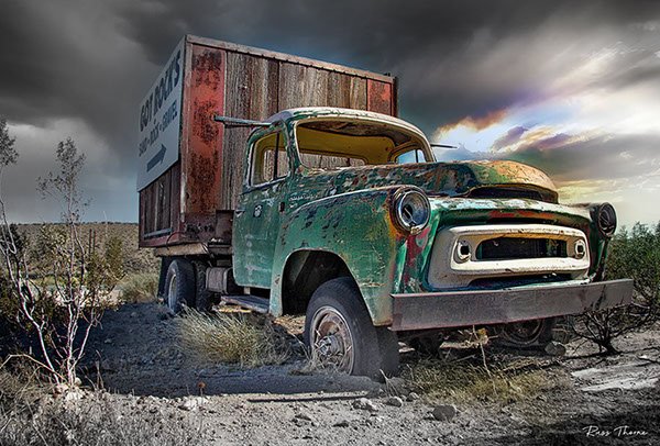 A rusty old box truck in the desert, repurposed as a highway billboard, marking the last job of this once-mighty vehicle.