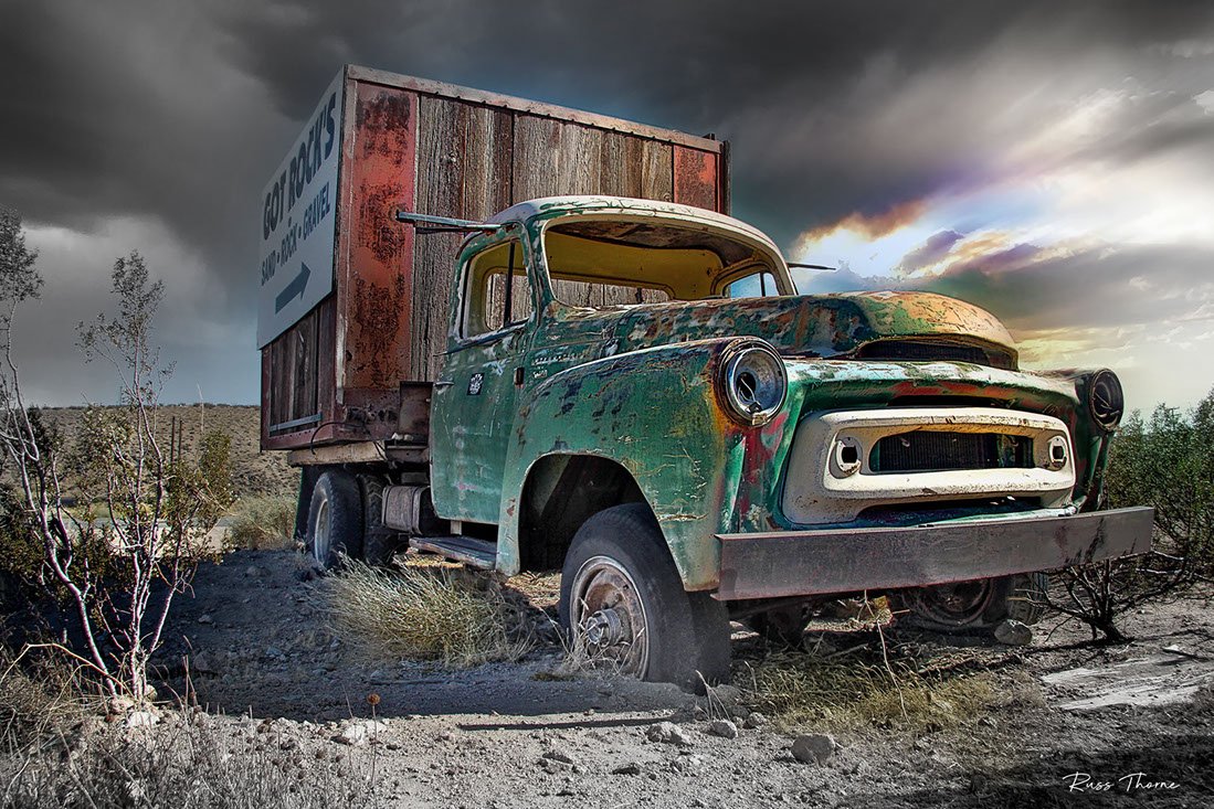 A rusty old box truck in the desert, repurposed as a highway billboard, marking the last job of this once-mighty vehicle.