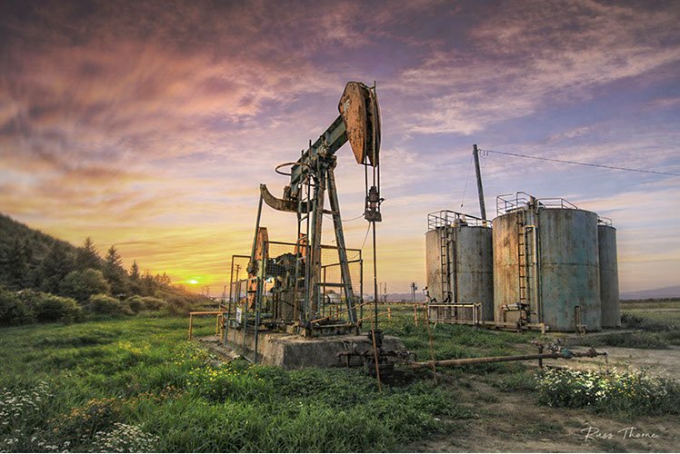 pump jack in Bakersfield california, a set of oil storage tanks in the background